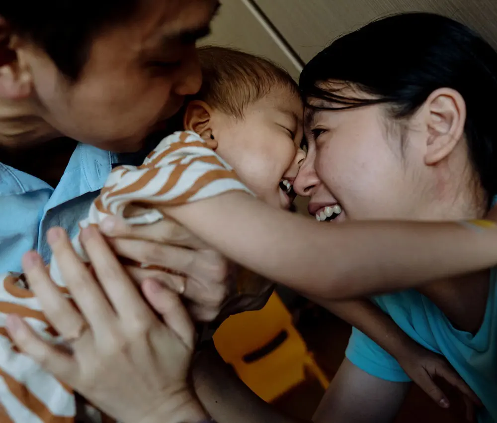 Close up of a family hugging their young child.